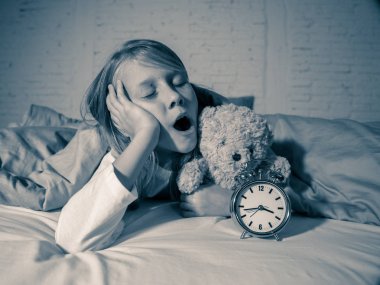 Geceleri uykuda kalmak veya çocuk uykusuzluk anksiyete ve uyku bozuklukları çok erken uyanma sorunları uyku sahip sevimli uykusuz küçük kız çalar saat seyir gösteren yatakta yatan yorgun.