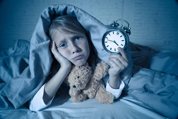 Симпатична Безсонна Дівчинка Лежить Ліжку Показуючи Будильник Який Виглядає Втомленим — стокове фото