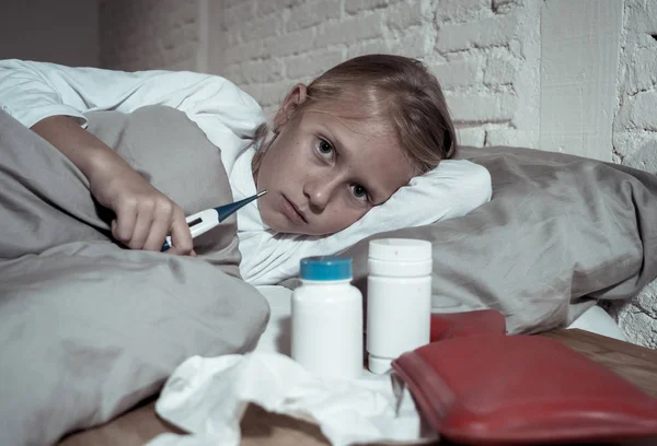 甜言蜜语生病可爱的女孩感觉生病躺在床上与药物温度计热水袋患有冷和冬季流感病毒打喷嚏和条纹疾病症状在儿童保健 — 图库照片