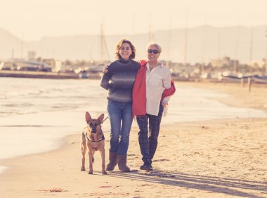 Mutlu kıdemli anne yetişkin kızı ve Alman shepard köpek vakit birlikte günbatımı ışık kumsalda mutlu aile anlarda evde beslenen hayvan hayvanlar yürürken köpek dostu Turizm ve emeklilik faydaları.