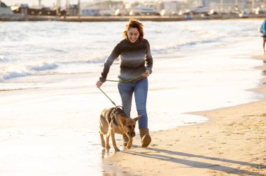 Güzel yetişkin kadın ve evde beslenen hayvan Alman shepard köpek arkadaşlık faydaları hayvanların köpeklerin yaşam tarzı ve köpek dostu Turizm Eğitim öğleden sonra batımında sahilde kıyı deniz okyanus yürüyen.