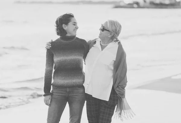 愉快的高级母亲和成年女儿一起度过的画像手牵手笑和走在海滩上日落光在快乐的家庭时刻世代退休和人的概念 — 图库照片