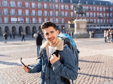 Genç turizm öğrenci adam onun yirmili mutlu ve heyecanlı hareket yukarı Plaza Mayor, Madrid, İspanya, gösterilen eğleniyor. Tatil, seyahat ve Avrupa ve özgürlük kavramı etrafında backpacking.