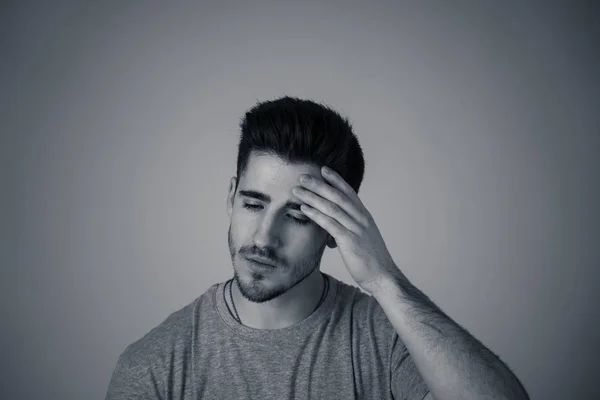 Close up portrait of handsome desperate young man suffering from depression looking miserable, melancholy and sad isolated on neutral background. In People, facial expressions and emotional pain.