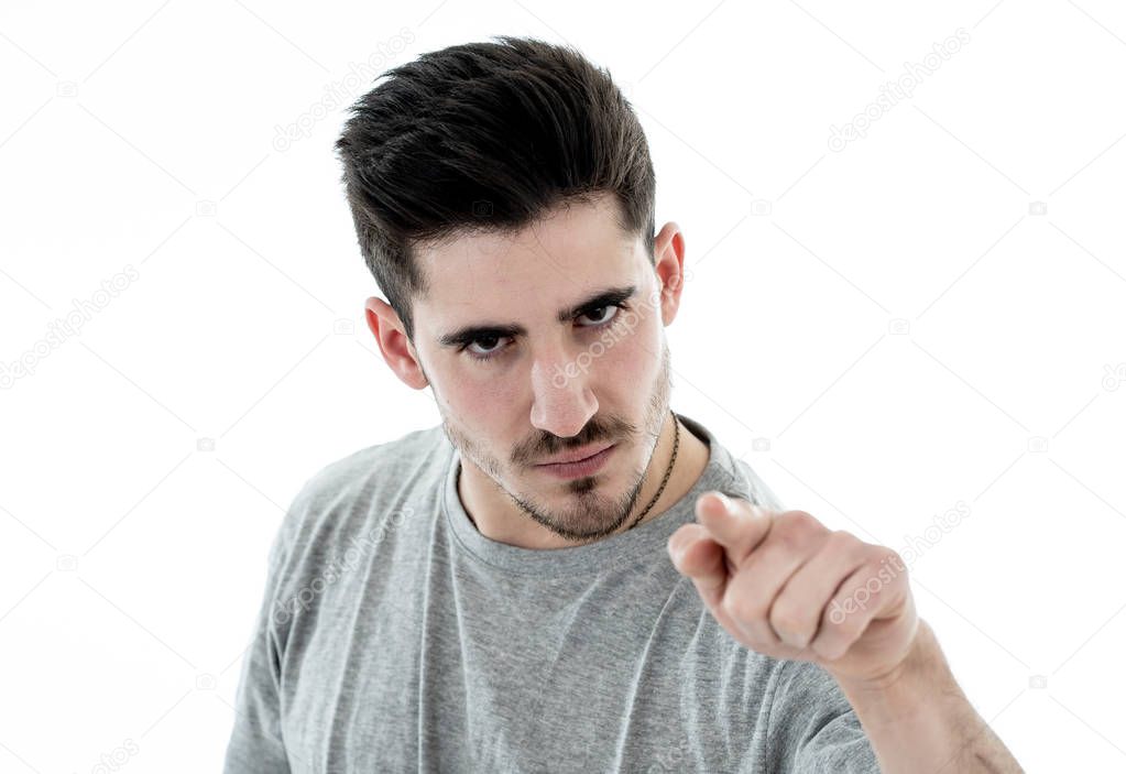 Close up portrait of young violent man with angry face looking furious and crazy showing fits and pointing finger at the camera. Human facial expressions, emotions and behavioral problems concept.