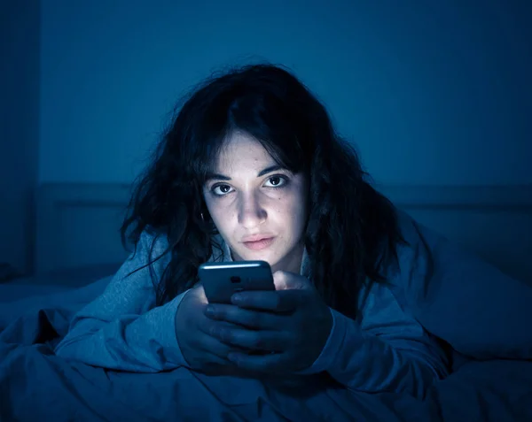 Mulher latina atraente viciada em telefone celular e internet no final da noite na cama olhando sem dormir — Fotografia de Stock