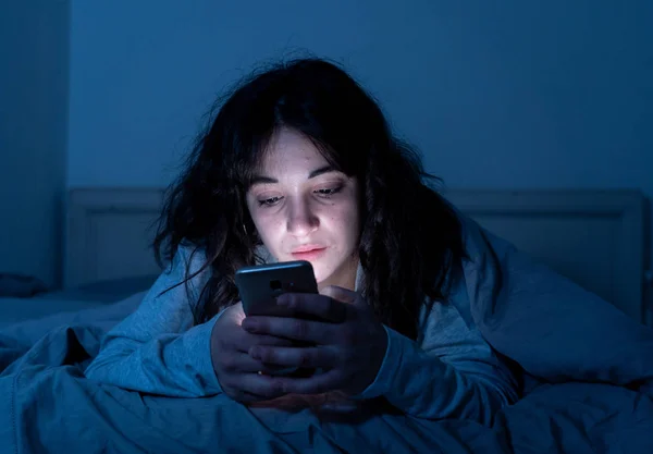 Mulher latina atraente viciada em telefone celular e internet no final da noite na cama olhando sem dormir — Fotografia de Stock