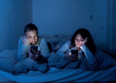 Akıllı telefonlarda geceleri yatakta genç sıkılmış çift portresi yaşam tarzı Oyunlar, sosyal medya, birbirimizi görmezden apps ile takıntılı. İlişki iletişim sorunları ve telefonu bağımlılığı konsepti.