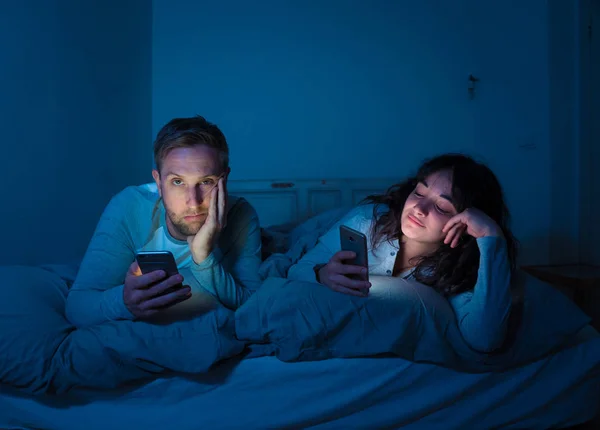 Retrato Estilo Vida Jovem Casal Entediado Cama Noite Telefones Inteligentes — Fotografia de Stock