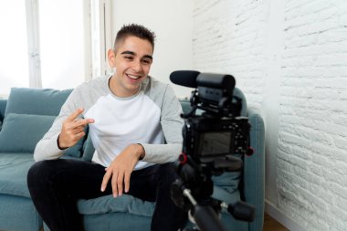 Kendi kendine portre fotoğraf çekim veya evde streaming video kaydı kamera tutarak rahat kıyafetler tarzı genç sevimli adam. Sosyal medya etkileyen, Internet takipçileri ve blogger kavramı.
