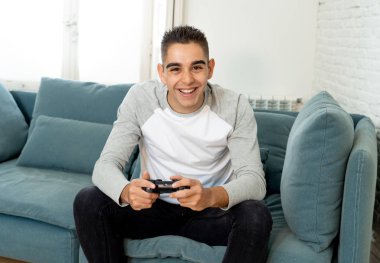 Video having oyunculuk ile konsol oyun İstasyonu ve video erkek oyun bağımlılığı ucube yoğun mutlu yüzüne kablosuz uzaktan joystick kullanarak oyunu kazanma oyunları oynamak genç öğrenci adam portresi.