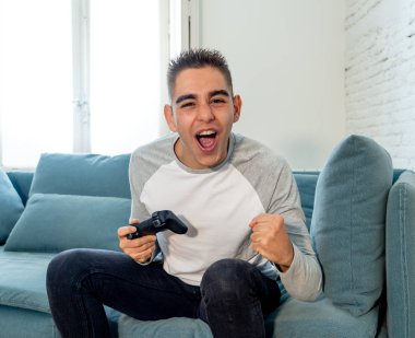 Video having oyunculuk ile konsol oyun İstasyonu ve video erkek oyun bağımlılığı ucube yoğun mutlu yüzüne kablosuz uzaktan joystick kullanarak oyunu kazanma oyunları oynamak genç öğrenci adam portresi.