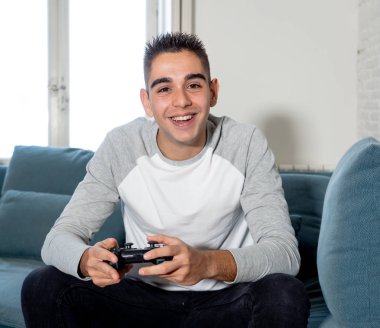 Video having oyunculuk ile konsol oyun İstasyonu ve video erkek oyun bağımlılığı ucube yoğun mutlu yüzüne kablosuz uzaktan joystick kullanarak oyunu kazanma oyunları oynamak genç öğrenci adam portresi.