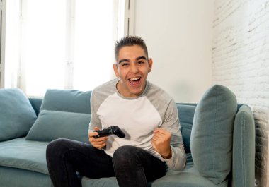 Video having oyunculuk ile konsol oyun İstasyonu ve video erkek oyun bağımlılığı ucube yoğun mutlu yüzüne kablosuz uzaktan joystick kullanarak oyunu kazanma oyunları oynamak genç öğrenci adam portresi.