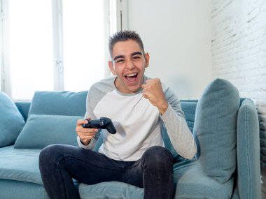 Video having oyunculuk ile konsol oyun İstasyonu ve video erkek oyun bağımlılığı ucube yoğun mutlu yüzüne kablosuz uzaktan joystick kullanarak oyunu kazanma oyunları oynamak genç öğrenci adam portresi.