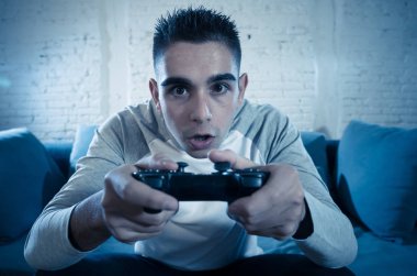 Ucube yoğun bağımlısı yüz erkek oyun bağımlılığı konsol oyun istasyonu ve video having oyunculuk ile kablosuz uzaktan joystick kullanarak gece video oyunları oynarken genç öğrenci adam portresi.