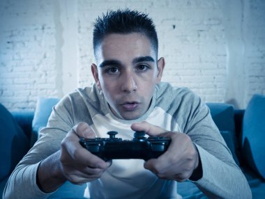 Ucube yoğun bağımlısı yüz erkek oyun bağımlılığı konsol oyun istasyonu ve video having oyunculuk ile kablosuz uzaktan joystick kullanarak gece video oyunları oynarken genç öğrenci adam portresi.