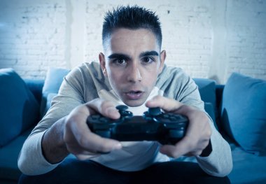 Ucube yoğun bağımlısı yüz erkek oyun bağımlılığı konsol oyun istasyonu ve video having oyunculuk ile kablosuz uzaktan joystick kullanarak gece video oyunları oynarken genç öğrenci adam portresi.