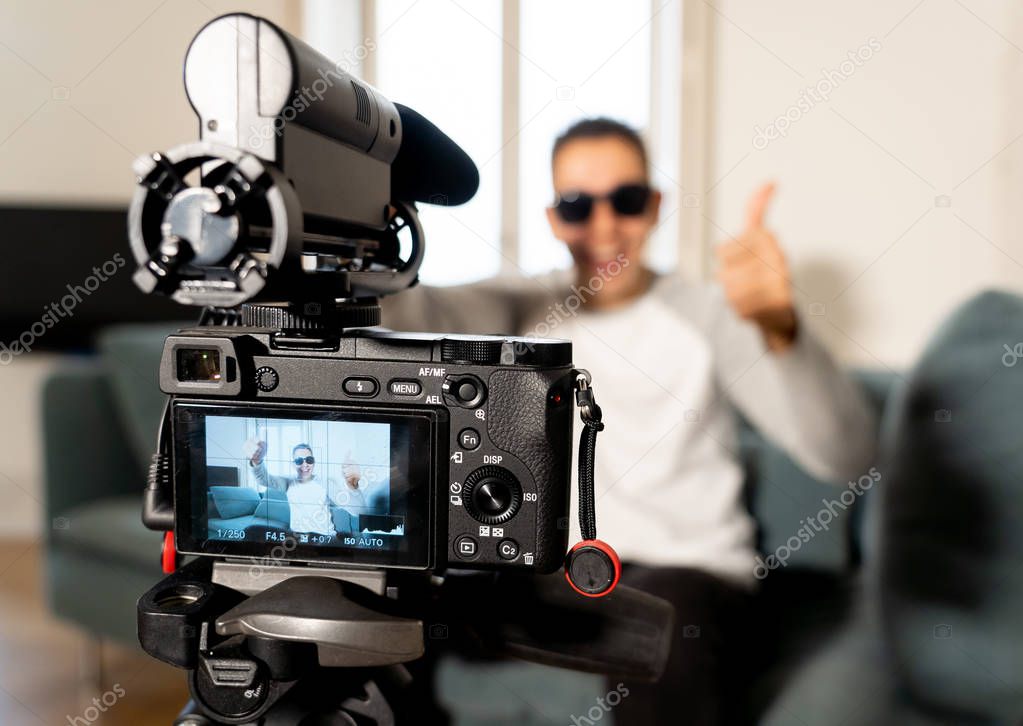 Close up image of camera screen on tripod recording a video blog with blurred Young happy man on his twenties on the background. In social media vlog, network,
