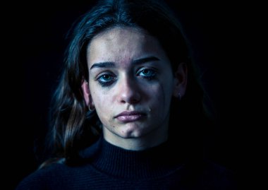 Ağlayan bir okulda, depresif, yalnız, yorgun, stresli genç çocuk kız closeup. Siyah arka plan üzerine izole. İnsan duyguları, çocukluk depresyon, duygusal acı. Zorbalık ve çocuk istismarı kavramı.