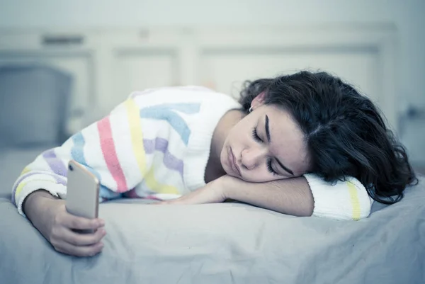 使用手机在床上的年轻美丽无聊的女孩特写镜头 厌倦了检查智能手机在忧郁的心情 通信互联网与技术成瘾和过度使用 手机依赖 — 图库照片