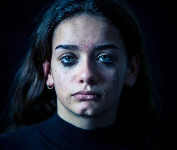 Scared upset girl bullied online suffering harassment crying feeling desperate and intimidated. Child victim of cyberbullying, stalker, social media and dangers of the Internet. Dramatic dark light.