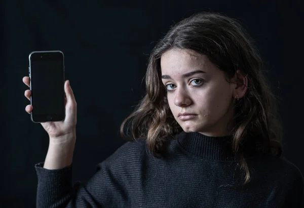 Scared upset girl bullied online suffering harassment crying feeling desperate and intimidated. Child victim of cyberbullying, stalker, social media and dangers of the Internet. Dramatic dark light.