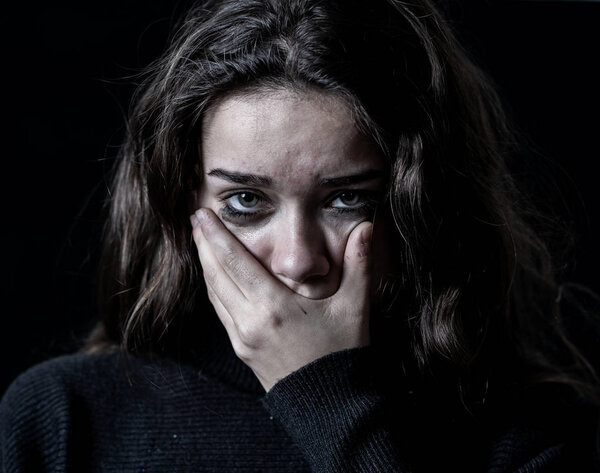 Драматический крупный план портрета молодой напуганной, подавленной девушки, плачущей в одиночестве, чувствующей себя безнадежной, страдающей от домогательств или домашнего насилия. Прекратить жестокое обращение с детьми и пренебрежение. Концепция социальной кампании
.