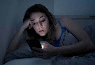 Sohbet ve telefon bağımlılığı ve teknoloji aşırı kavramı gece geç saatlerde akıllı telefonunu uykulu, donuk ve yorgun kullanarak Internet sörf bağımlısı genç güzel kadın yatakta,.