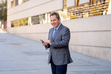 Orta yaşlı yakışıklı işadamı ofiste Kentsel şehir dışında cep telefonu app gönderen iletisinde kullan