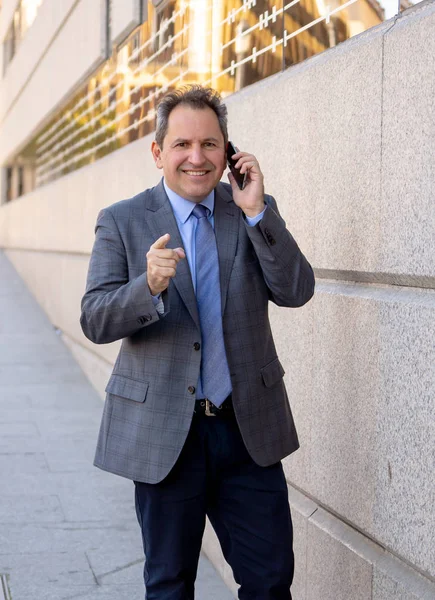 Retrato de un guapo hombre de negocios inteligente de mediana edad caminando por la ciudad hablando por teléfono móvil — Foto de Stock