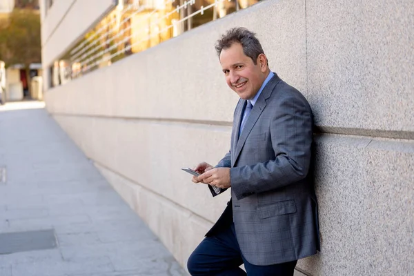 Hombre de negocios guapo de mediana edad utilizando la aplicación de teléfono móvil enviar mensaje fuera de la oficina en la ciudad urbana —  Fotos de Stock