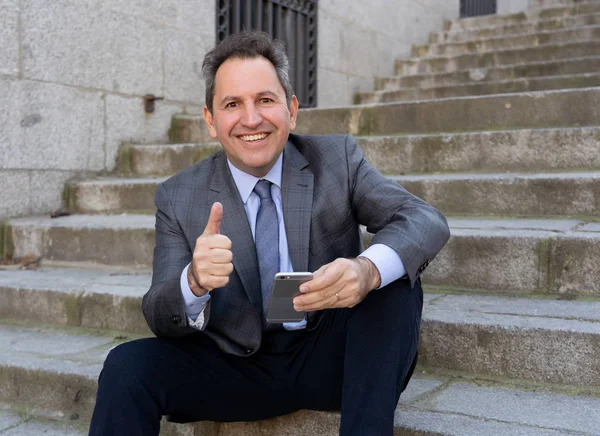 Empresário de negócios maduro feliz homem sentado ao ar livre escadas urbanas trabalhando e usando telefone inteligente — Fotografia de Stock