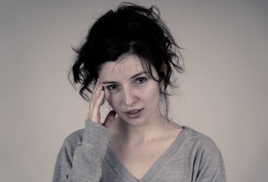 Genç üzgün bir kadının yakın, ciddi ve endişe, kafasına dokunmadan ve endişeli ve düşünceli görünümlü. Beyaz arka planda yalıtılmış. Yüz ifadeleri ve duygular kavramı.