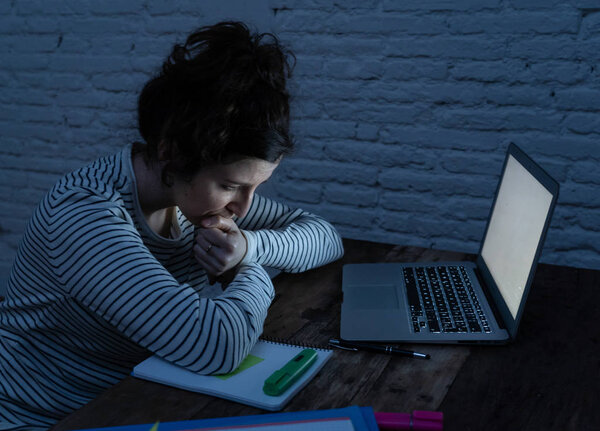 Переутомленная и уставшая студентка работает допоздна за своим ноутбуком, стараясь не заснуть, чувствуя усталость, беспокойство и грусть. Мрачный темный свет. Концепция онлайн обучения и работы со стрессом
.