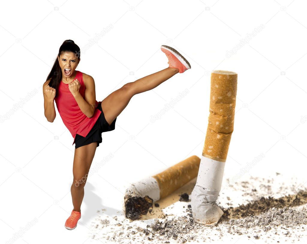 Young beautiful furious woman determined to stop smoking kicking and breaking a huge cigarette butt with strong will power. In anti smoking and quit tobacco addiction for healthy lifestyle concept.