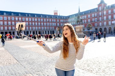 Güzel genç Kafkas kadın mutlu ve heyecanlı Plaza Mayor Madrid kendini bir fotoğraf çekici. Neşeli, poz ve V-sign iş arıyorum. Avrupa'da seyahat etmek turizm, Avrupa şehri,.