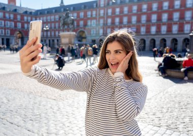 Güzel genç beyaz öğrenci turist kadın bir selfie veya onu turizm ve seyahat etmek çevrede Dünya blog web Plaza Mayor Madrid İspanya için video alma. Sosyal medya ve Avrupa'da tatil.