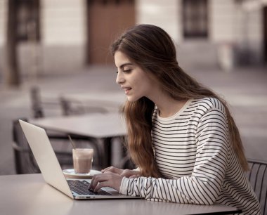 Çalışma veya kahve dükkanında dışında onun dizüstü bilgisayarda eğitim genç ve güzel neşeli kadın içme kahve. Mutlu ve memnun hissediyorum. Girişimci, online eğitim ve teknoloji kavramı.