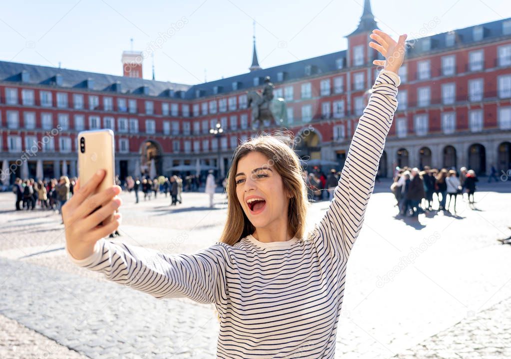 Beautiful young caucasian student tourist woman taking a selfie or video for her tourism and travel around the world blog web in Plaza Mayor Madrid Spain. In social media and vacations in europe.