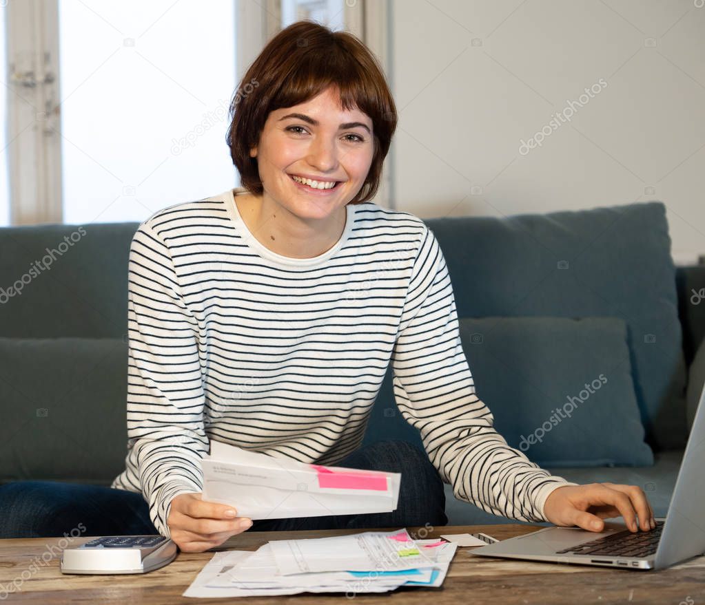 Happy woman with laptop feeling successful accounting home finances calculating costs, charges, mortgage, taxes and paying bills. In e-banking, e-commerce and home or small business accountant.