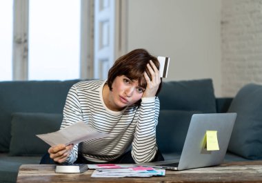 Duygu endişeli ve umutsuz kadın portresi ödeme kredi kartı borçları ve evde kanepede dizüstü bilgisayarda faturaları vurguladı. İş ve ev mali ve mali sorunlar kavramı.