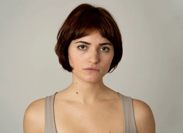 Close up of a young sad woman, serious and concerned, looking worried in emotional pain. Feeling sorrow and depression. Isolated in neutral background. In facial expressions and emotions concept.