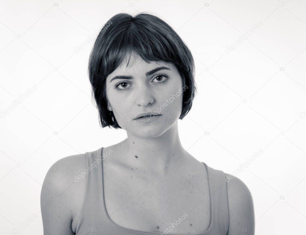 Black and white portrait of young sad woman, serious and concerned, looking worried and disgusted. Staring at the camera with stern look. White copy space. Unhappy emotions and expressions concept.