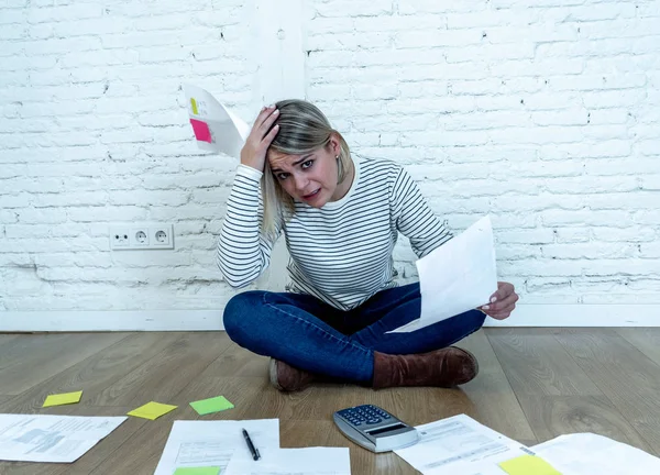 Portrait of worried young woman feeling stressed and desperate on the ground with calculator accounting expenses not able to pay mortgage. In paying debts and domestic bills and financial problems.