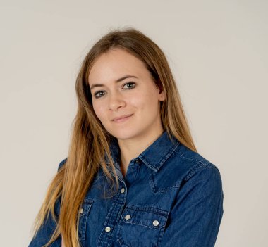 Küçük güzel genç kadının stüdyo portresi, sarı saçlı, kendine güvenen, rahat poz veren ve modelleme yapan Jean shirt giyiyor. Nötr arka planda izole. Yaşam tarzı ve güzellik konsepti.