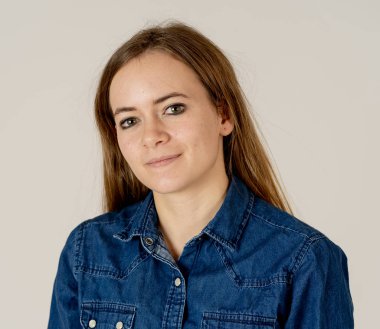 Küçük güzel genç kadının stüdyo portresi, sarı saçlı, kendine güvenen, rahat poz veren ve modelleme yapan Jean shirt giyiyor. Nötr arka planda izole. Yaşam tarzı ve güzellik konsepti.