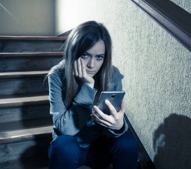 Siber zorbalık istismarı muzdarip online Stalker genç kız kurbanı yalnız ve umutsuz koyu ışık merdivenlerde oturan duygu. İnternet tehlikeleri, çevrimiçi bakım ve taciz konsepti.