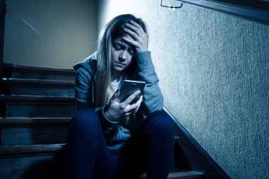 Siber zorbalık istismarı muzdarip online Stalker genç kız kurbanı yalnız ve umutsuz koyu ışık merdivenlerde oturan duygu. İnternet tehlikeleri, çevrimiçi bakım ve taciz konsepti.
