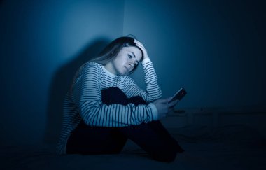 Online BULLING ve taciz yalnız ve umutsuz gece yatakta oturan felling acı akıllı telefonda üzücü umutsuz genç ergen kadın kız. Siber zorbalık ve internet kavramının tehlikeleri.